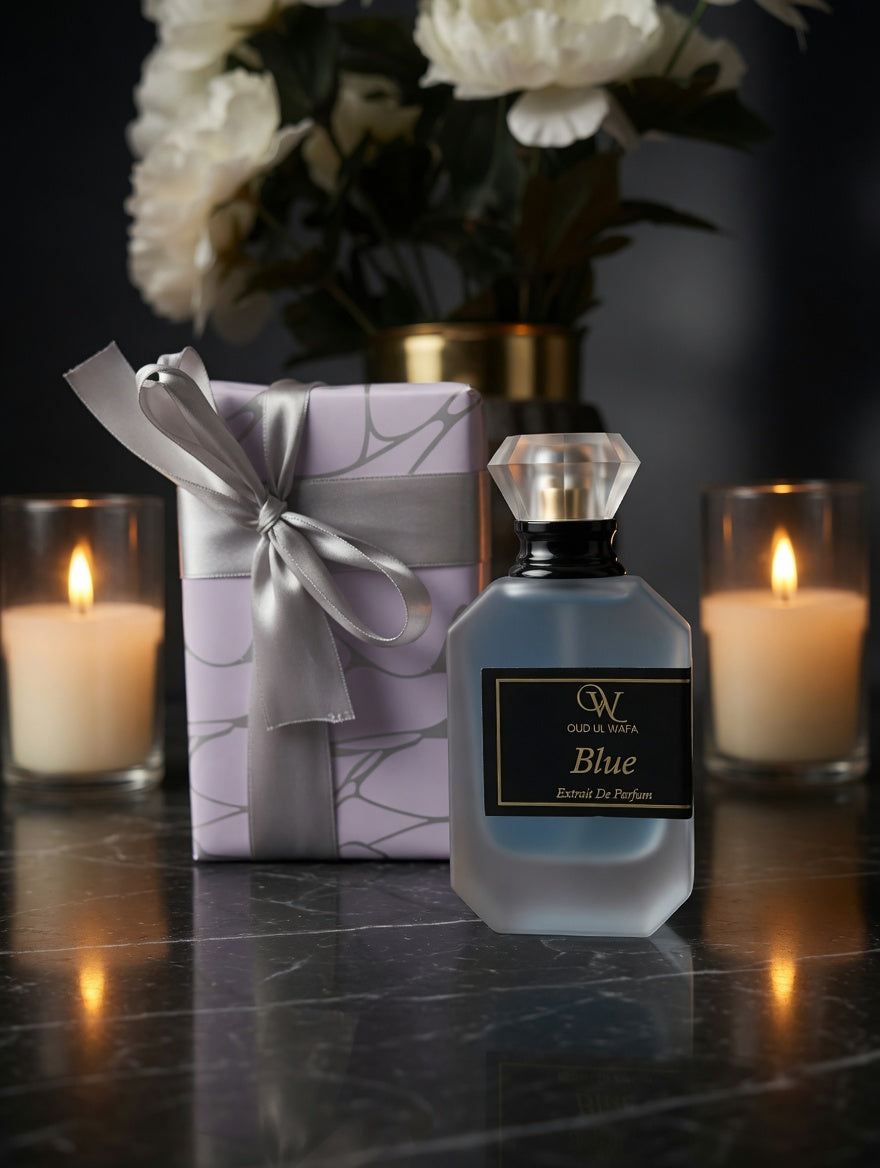 Perfume bottle labeled 'Blue' with a gift box and candles on a dark surface