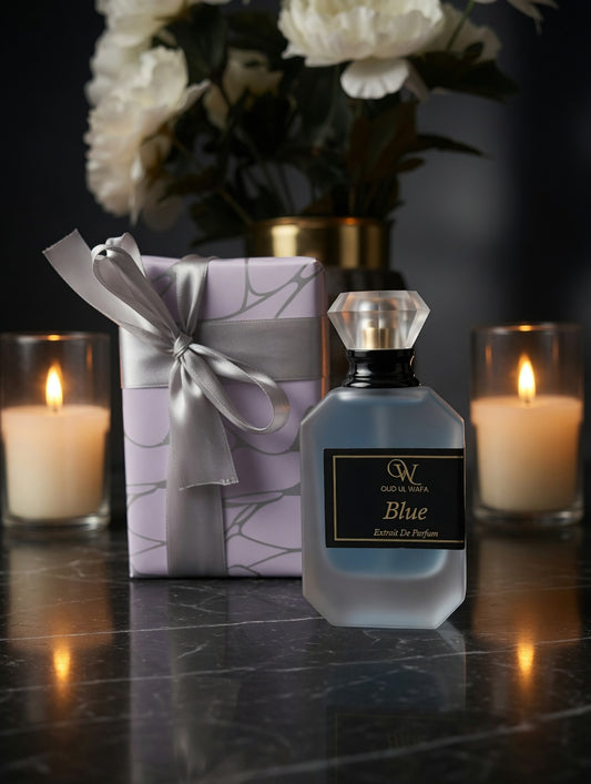 Perfume bottle labeled 'Blue' with a gift box and candles on a dark surface