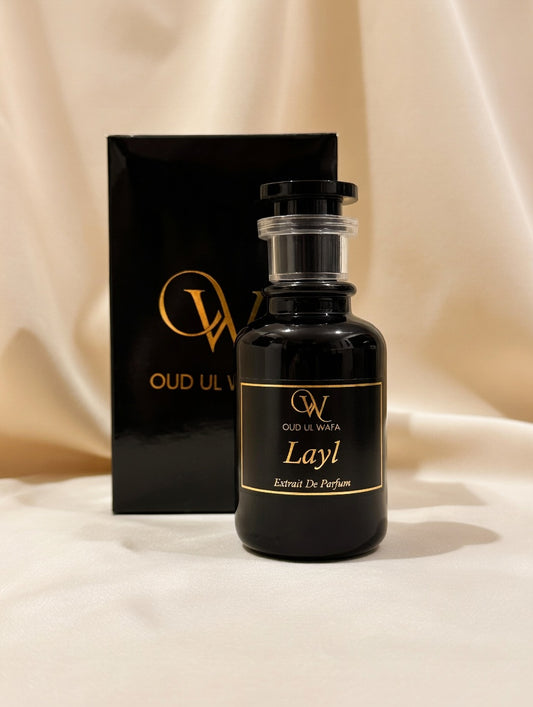 Black perfume bottle with gold text on a beige fabric background